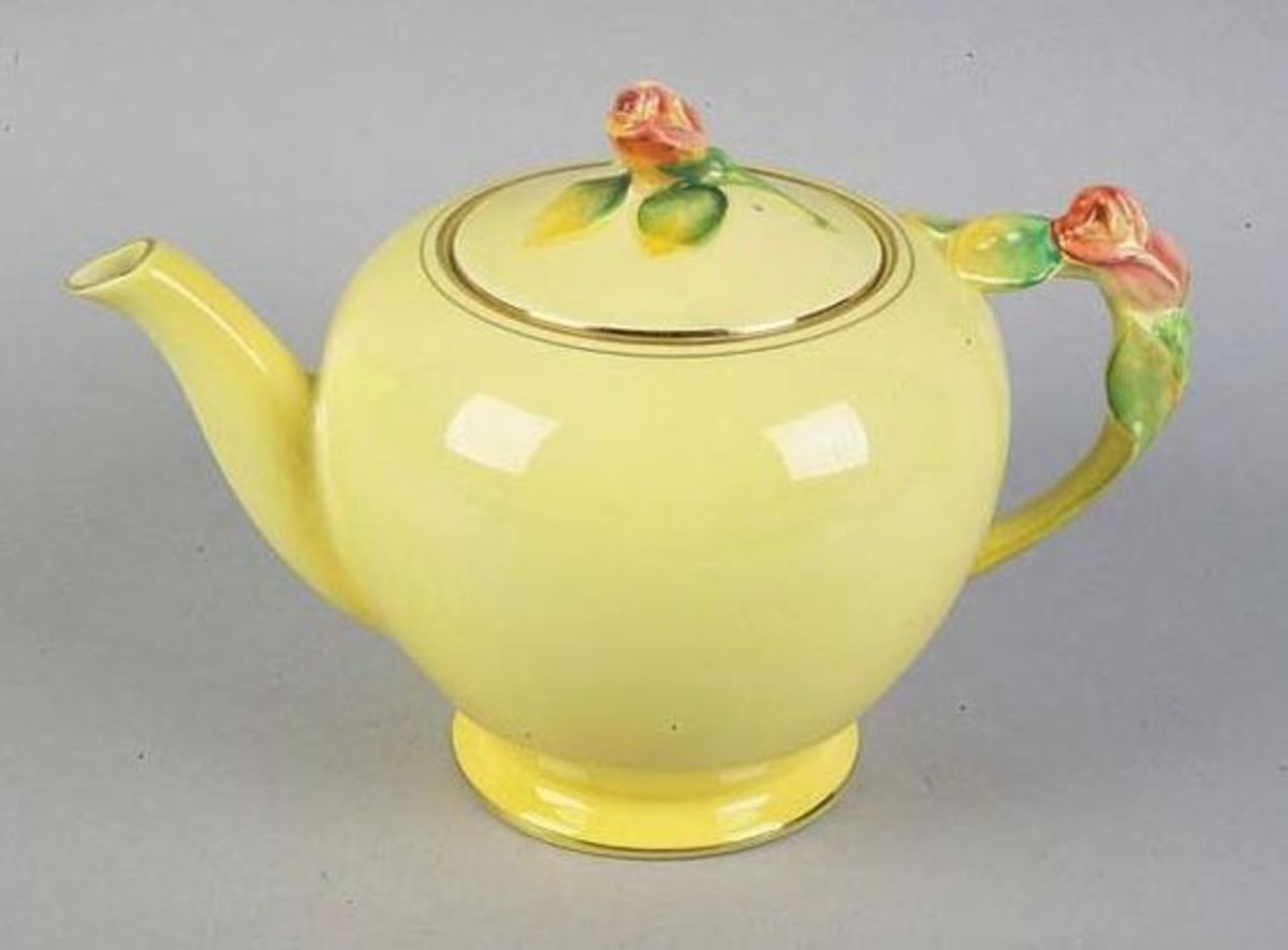 A sweet sculpted rosebud adorns this pot.