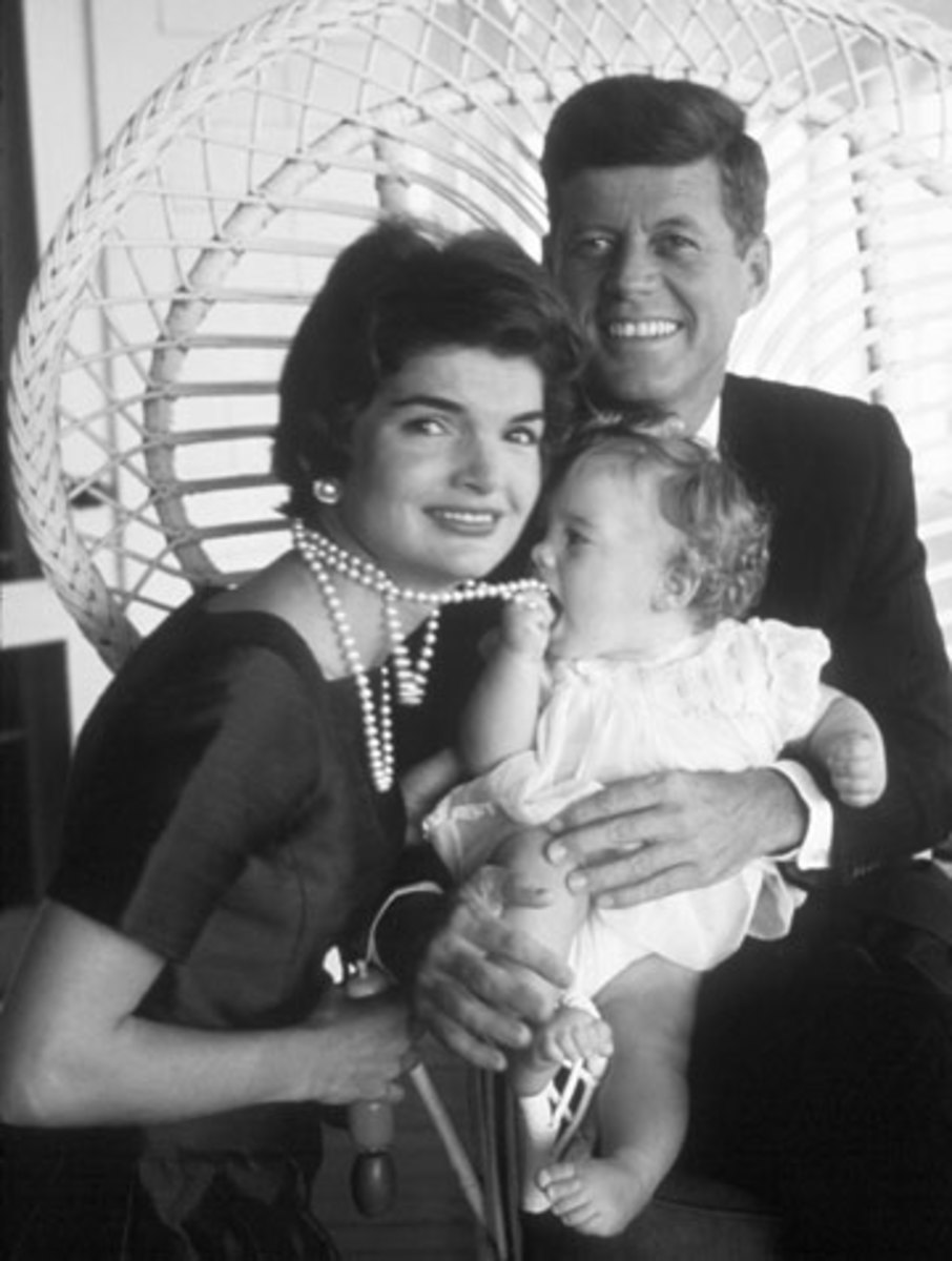 black and white photo of Jackie Kennedy and JFK and Carolyn holding a strand of pearls