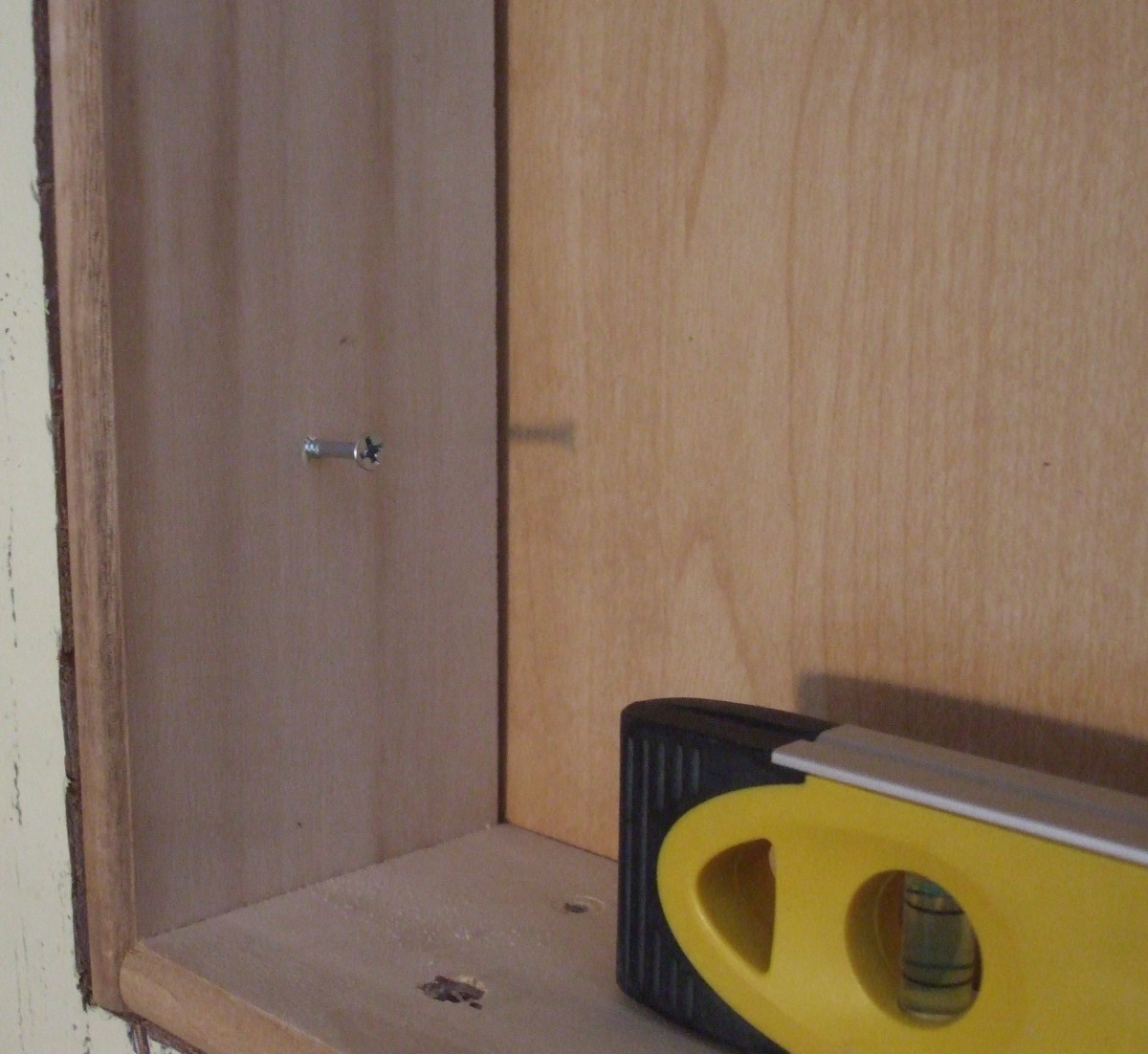 The screw was started in the side of the box, but no pilot hole was made in the stud until the level gave its approval. 