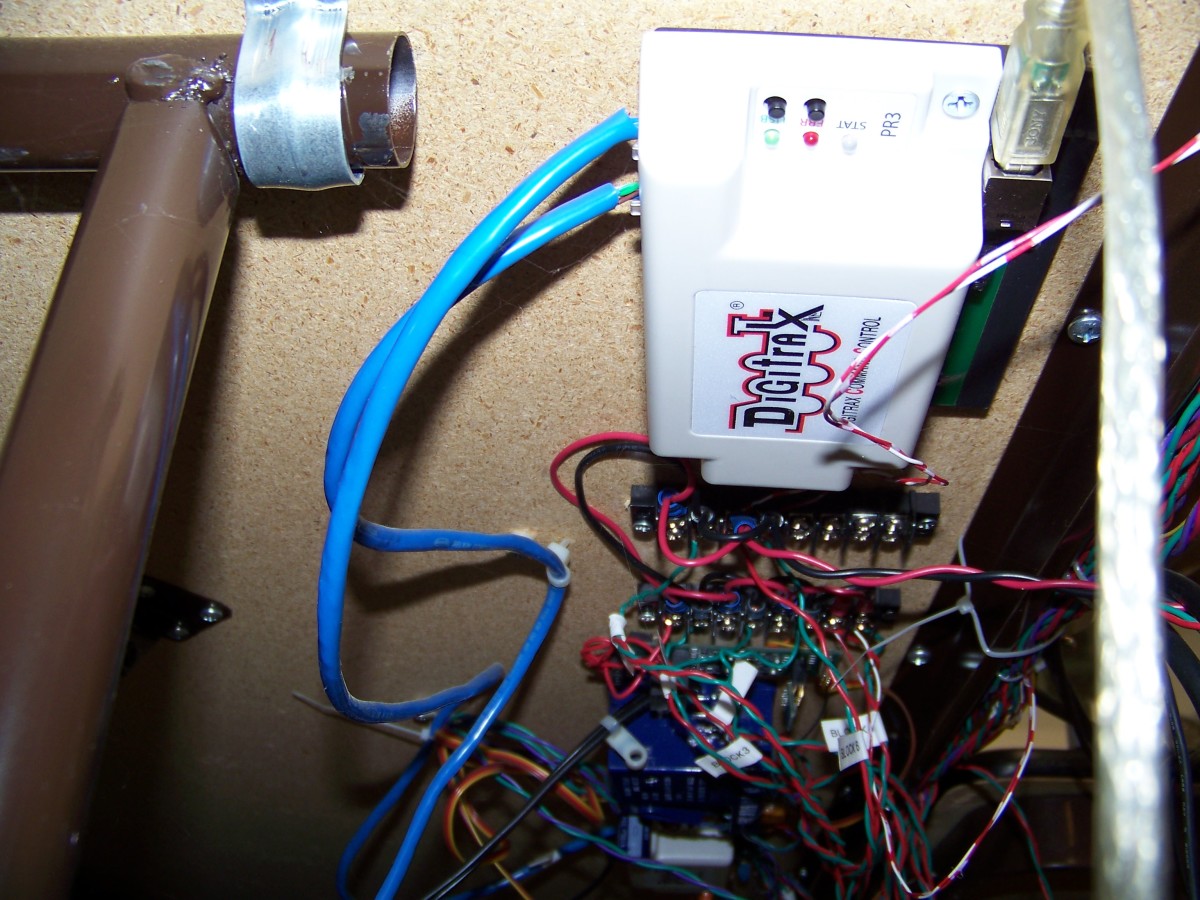 I mount my Digitrax  PR3 computer interface, along with other electronic components, to the front bottom of the MDF board that makes the tabletop. This puts the electronic components close to the exposed wiring.  