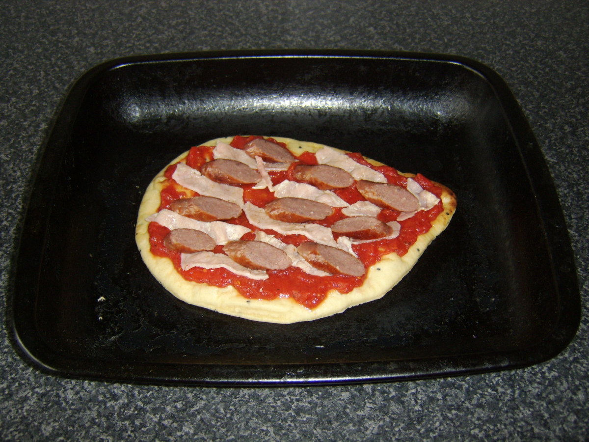 The sausage and bacon is spread evenly and alternately on the tomato sauce