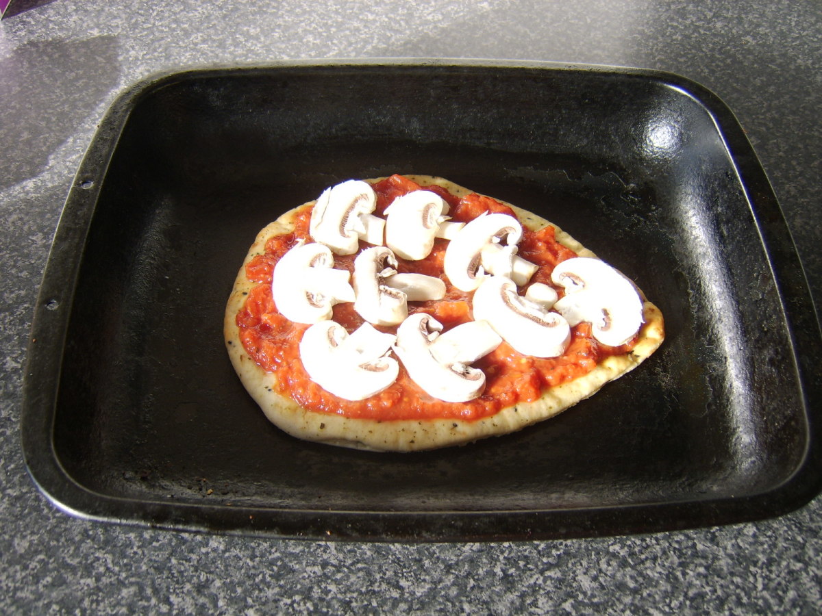 The mushroom slices are added first to the pizza