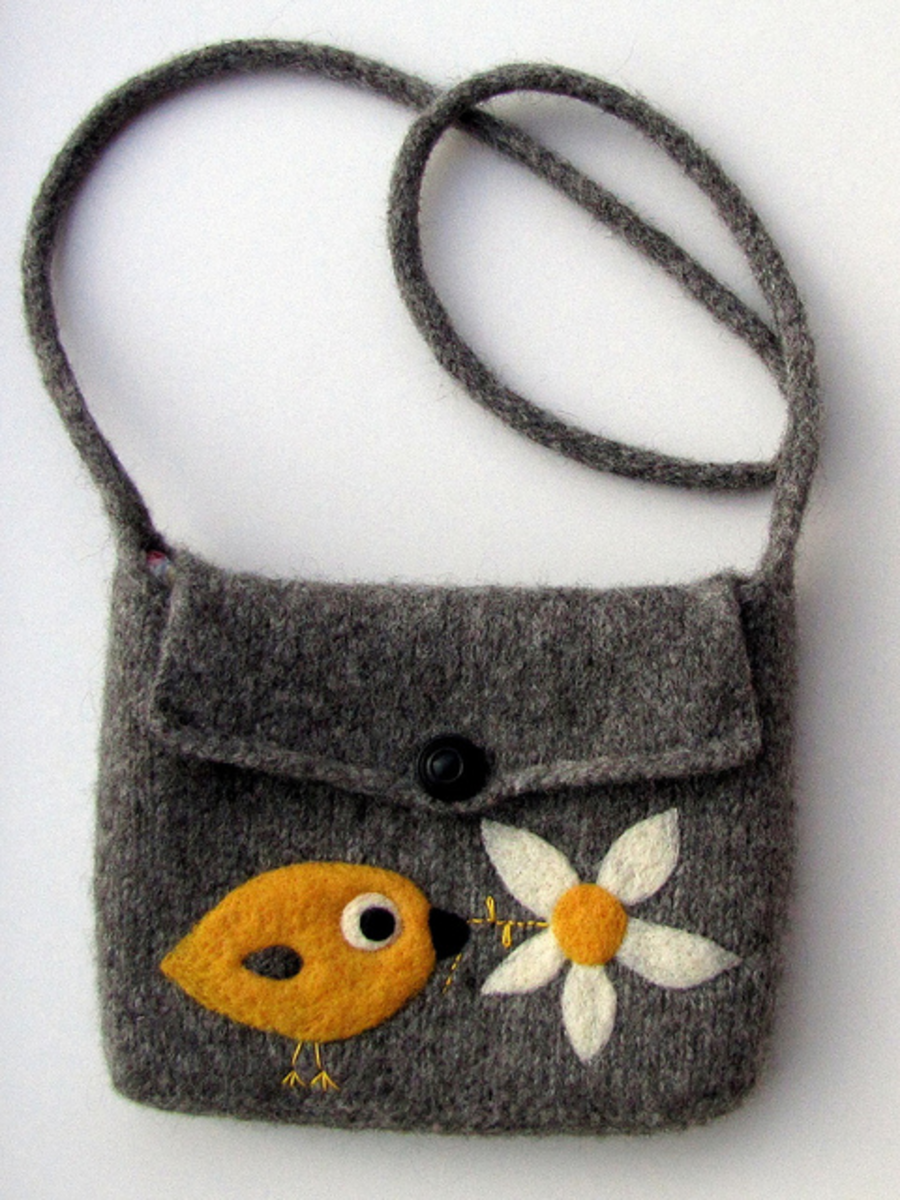 This bag was hand knitted in wool, then (washing) machine felted. The bird and flower embellishments were needle felted onto the bag.
