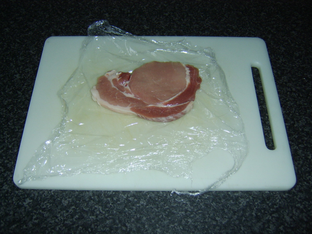 Meat fillet is placed on a sheet of plastic wrap, seasoned and covered with a second sheet of wrap