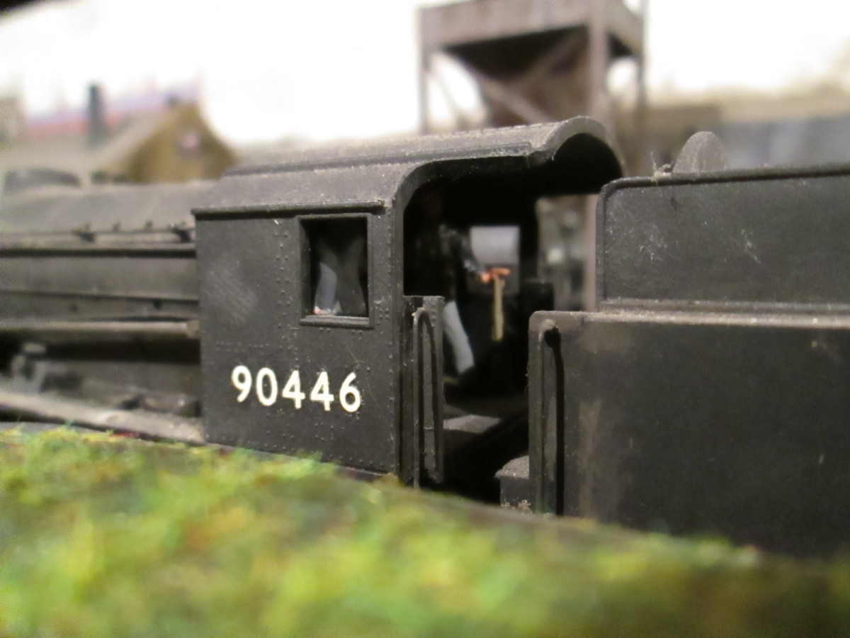 Bachmann Riddles' ex-War Department 2-8-0 seen over the roof of a grounded and overgrown canvas roofed van body  - you can just about make out the fireman on the far side of the cab, the driver with his back to you, 