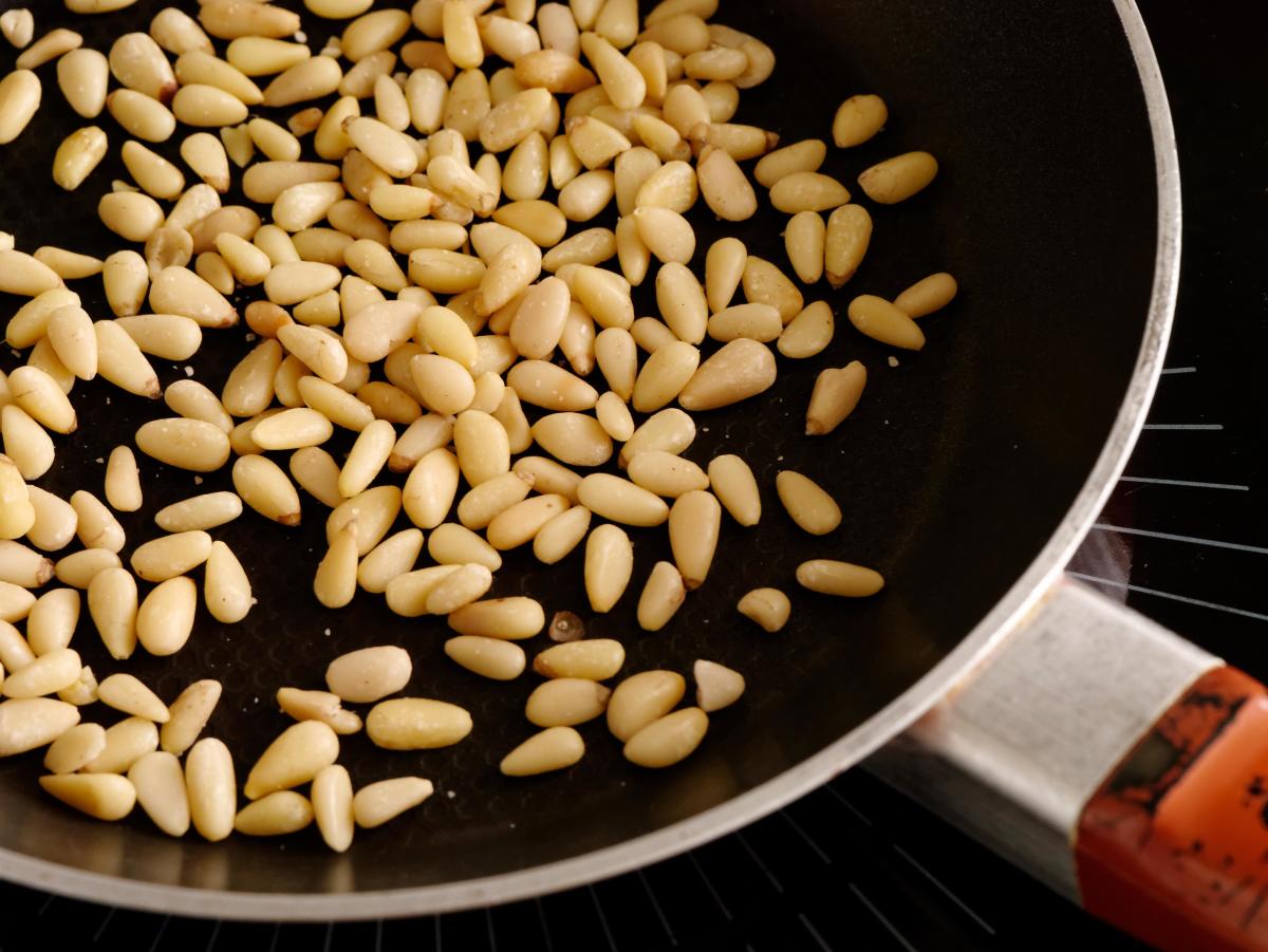 Pine nuts being toasted in a frying pan
