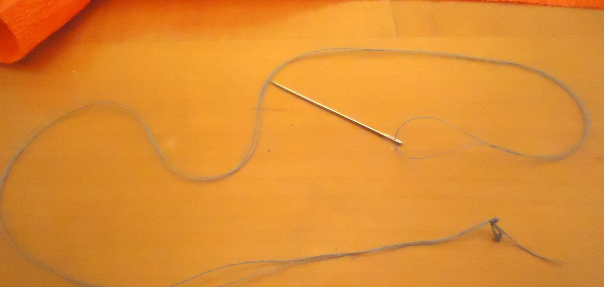 Threaded needle with large knot.