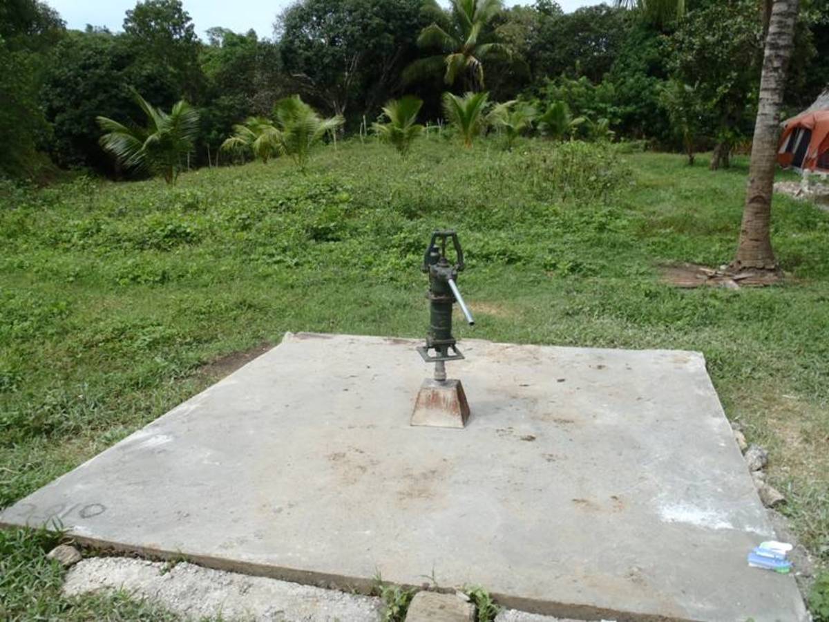 Hand pump installed on the well and a 16x16 cement slab.
