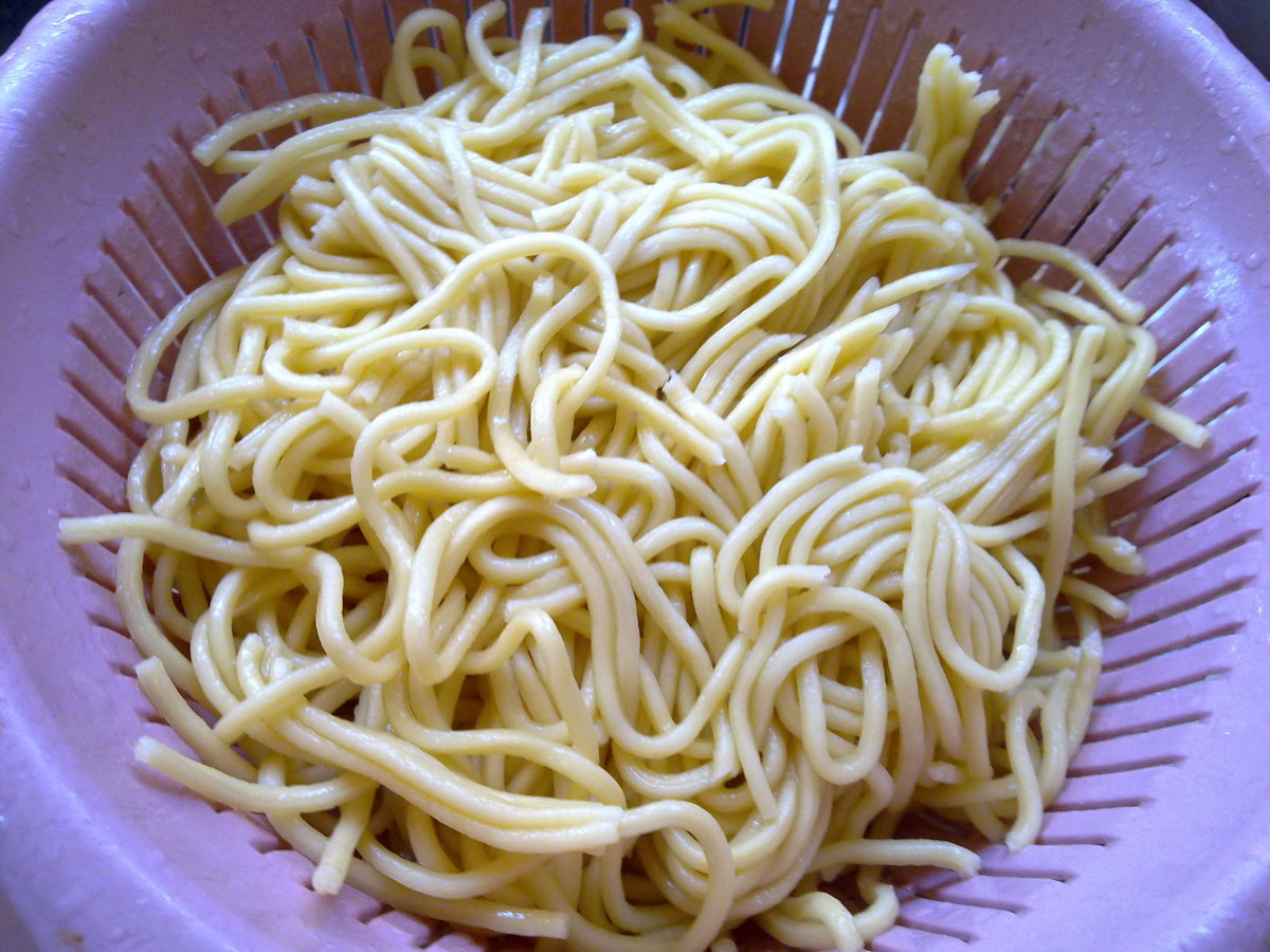 yellow noodles being strain with a colander