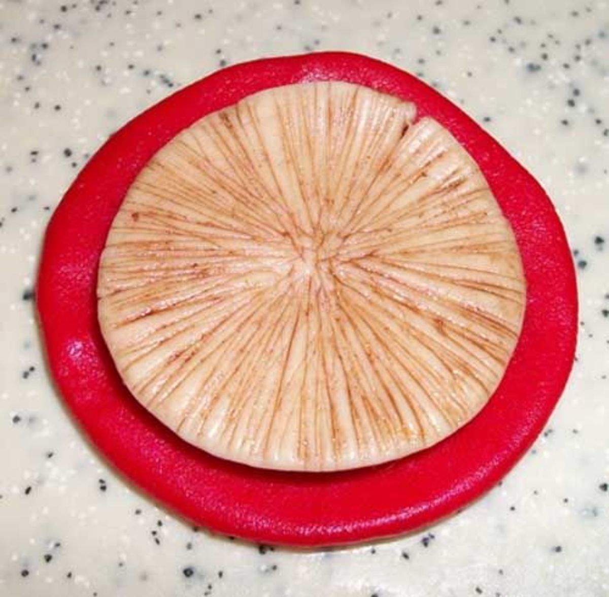 Press the red fondant circle on top of the off-white circle.