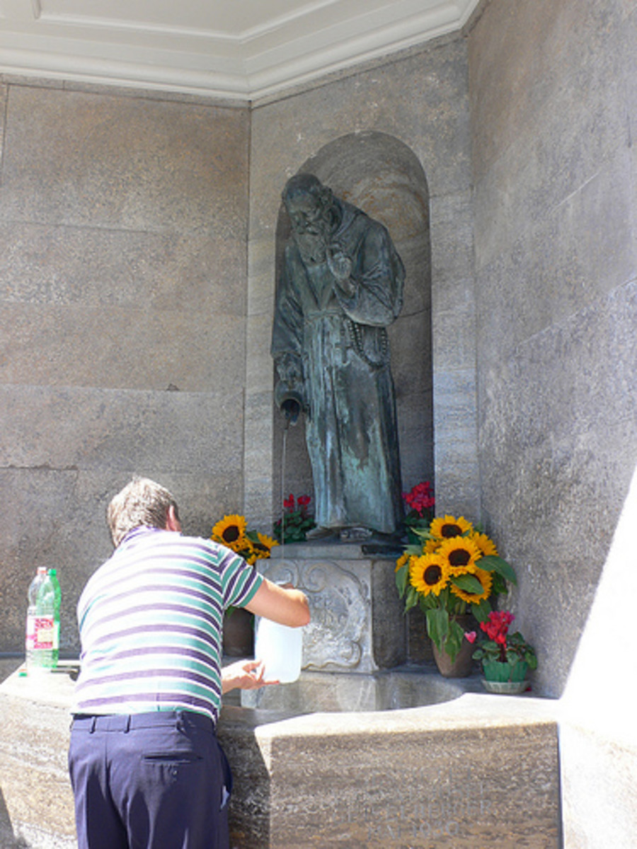 A visitor prays before a statue of Saint Conrad of Parzham.