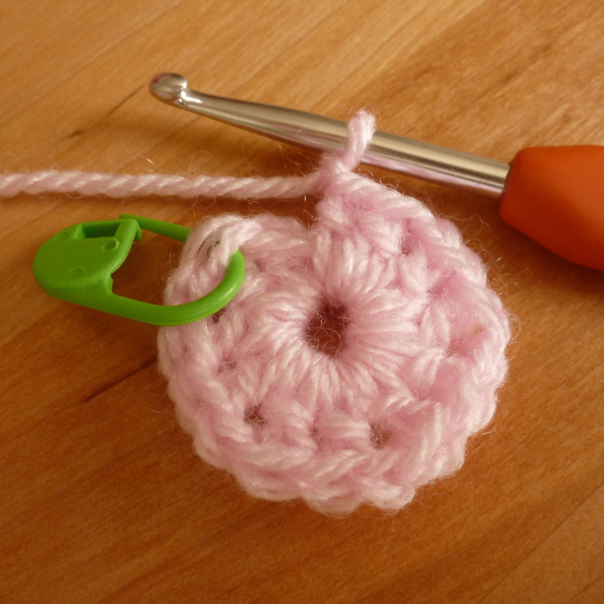 Working a circular round of crochet, using a stitch marker to show where you started the round.