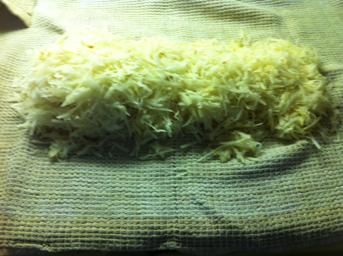 Place grated potatoes onto a tea towel and roll to get the moisture out.