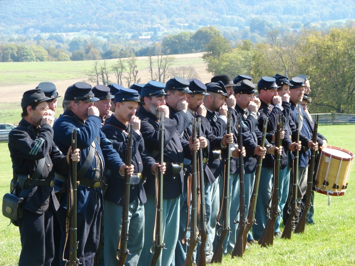 Members of the 8th Ohio Volunteers Living History Association tear cartridges (bite-off the tapered bottoms) with their front teeth