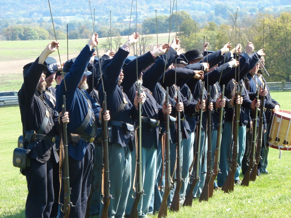 Members of the 8th Ohio Volunteers Living History Association draw their rammers in order to ram the cartridges down to the bottoms of the barrels