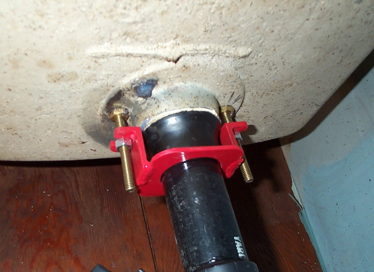 My father had to manufacture a fitting and bracket for the drain, as we could not locate one with the correct design. He heated and flared a new pipe, using a lathe to achieve a bell-shape. He also modified brass toilet bolts to work with the clamp.