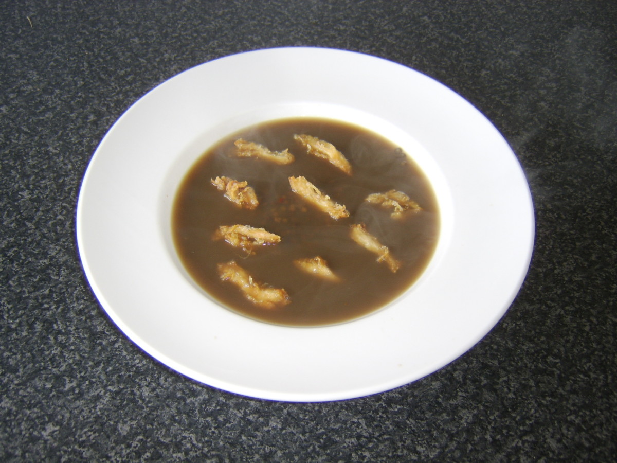 Deep fried crispy chicken strips are scattered over a spicy green lentil, chilli and garlic soup