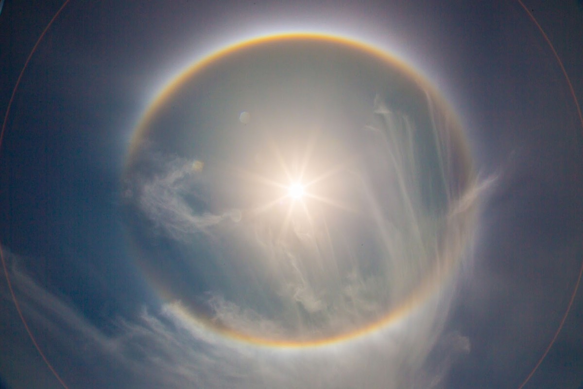 This Sun Halo clearly shows the rainbow-like circle that is indicative of Sun Halos and lens flares that might be mistaken as planets around the Sun. Science explains this as caused by ice particles in the atmosphere, might there be another cause? 