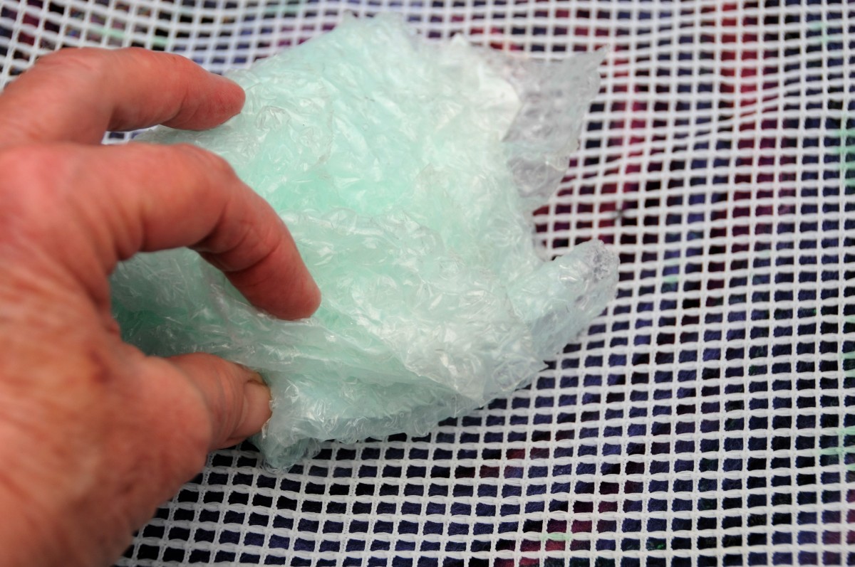 Rubbing the wet fibers below the curtain netting with a piece of folded bubble-wrap.  Rub until the fibers no longer move.