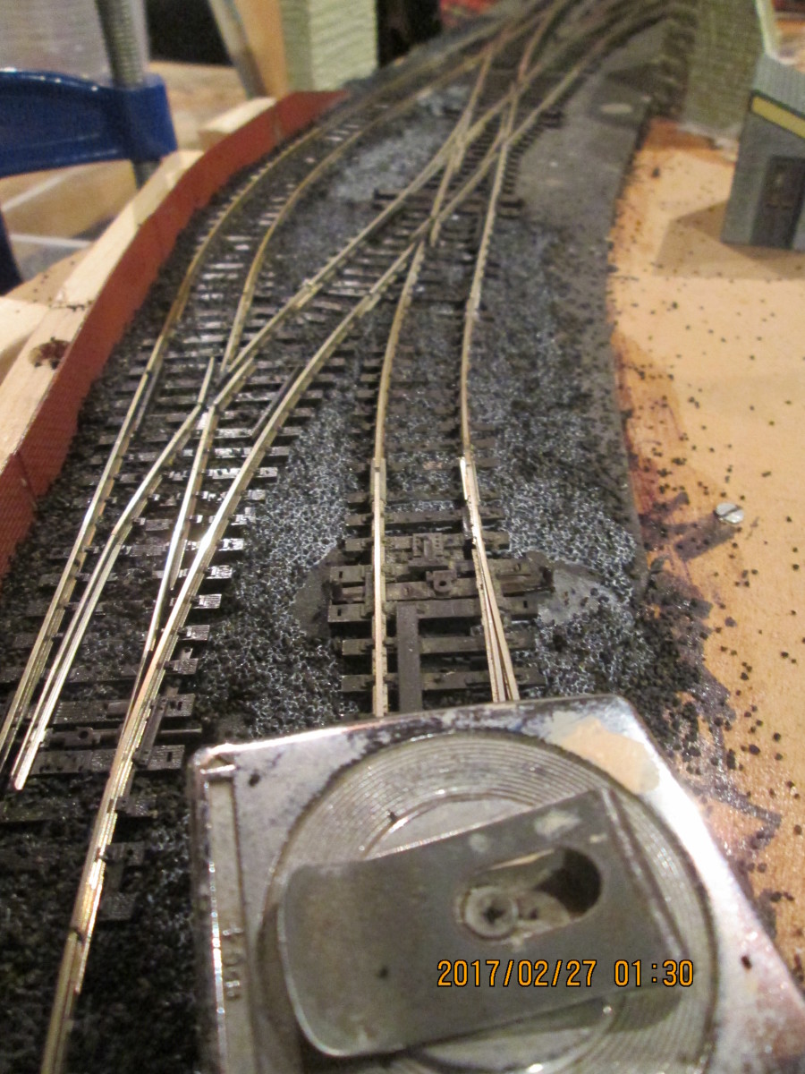 With the platform road ballasted, time to work towards and around the pointwork. Use heavy-ish tools to weigh down ballasted track until it's set. Give it 24-48 hours in dry cellar conditions