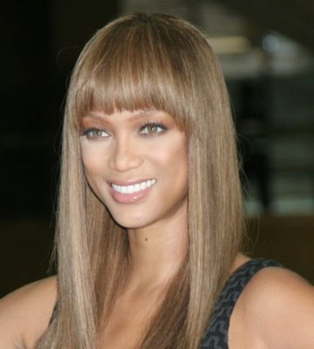Tyra Banks with dark ash blonde hair color, in a long straight wig with bangs. Celebrities with dark ash blonde hair color.