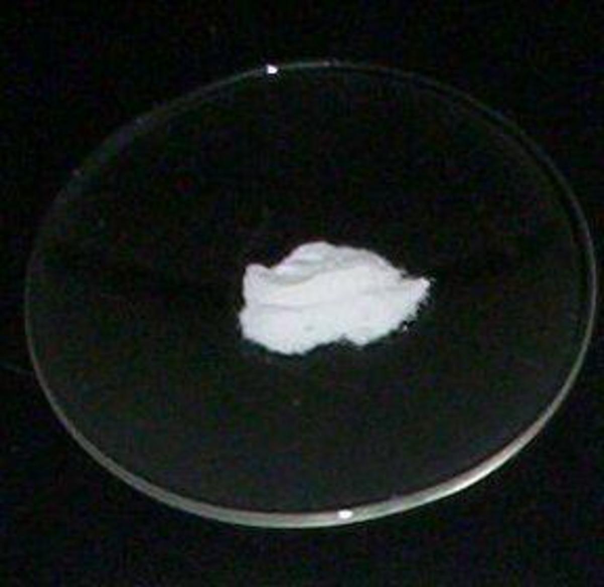This is a watch glass, which as you can see, has a small dip in the centre. The powder in the centre is caesium fluoride.  