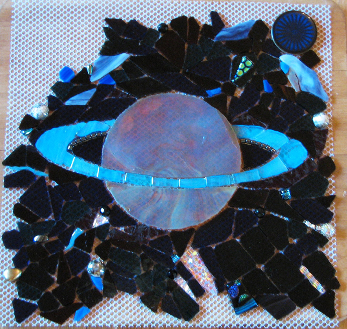 This is a small piece of a much larger mosaic featuring outer space, stained glass, costume jewelry, pearls, beads, and dichroic glass on mesh, to be applied to Wedi.  