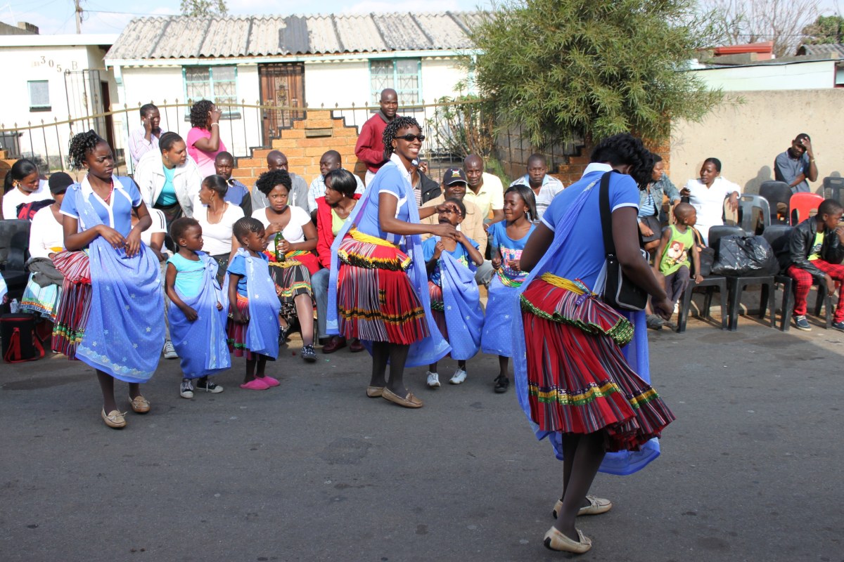 Wmen and children dancing int the streets singing traditional songs and dances