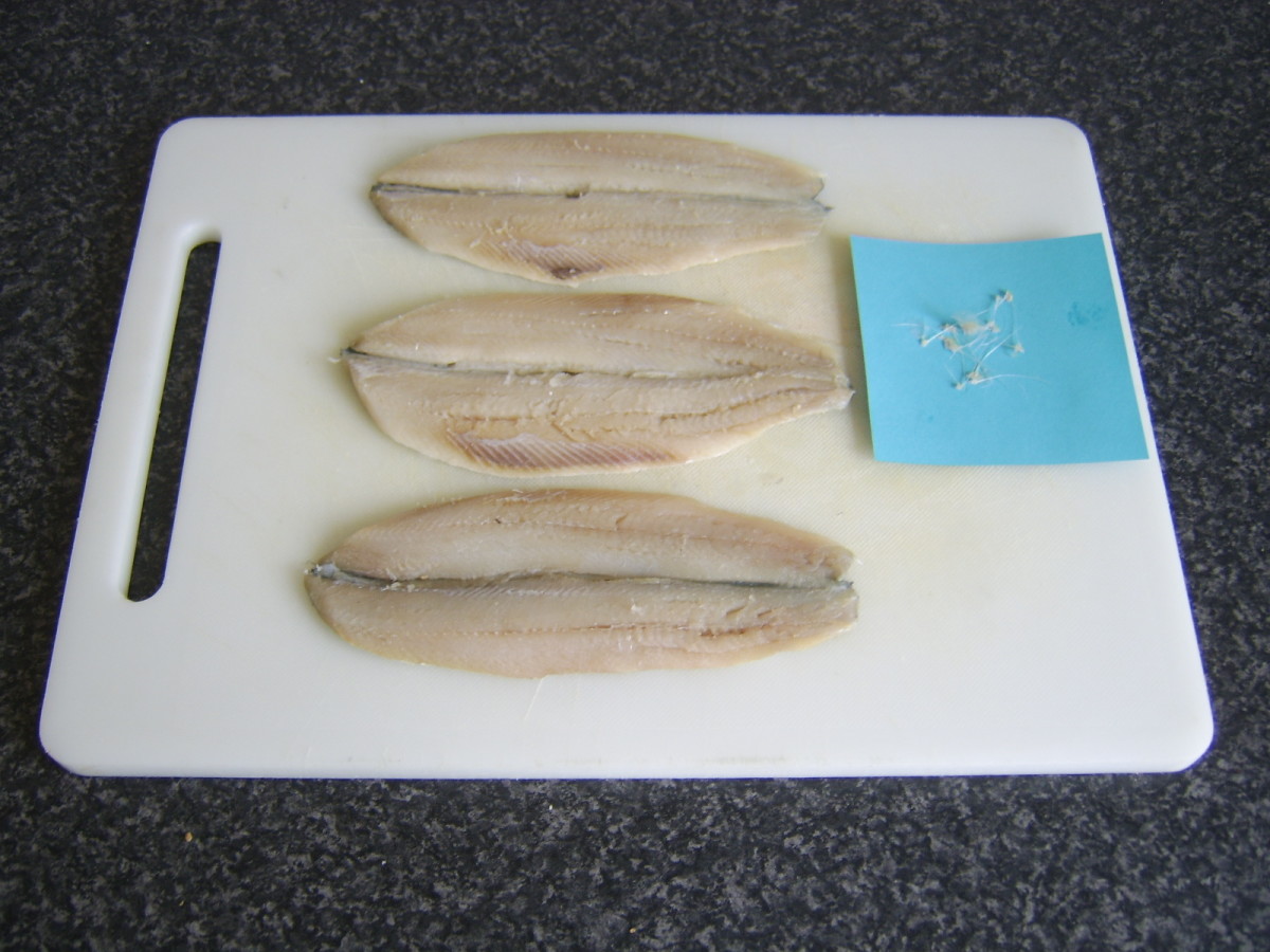 The bones removed from these herring fillets have been laid on a piece of blue paper to hopefully make them more readily visible
