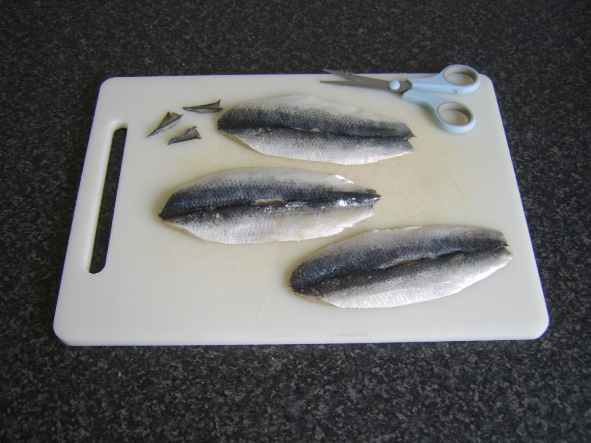 Dorsal fins are snipped from herring fillets with kitchen scissors
