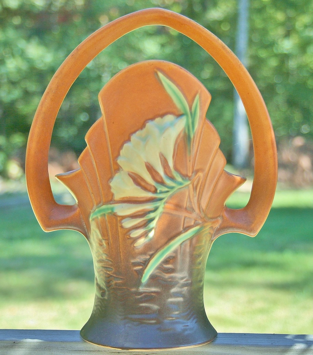 A Roseville basket vase with two-tone orange/brown background & freesia motif.