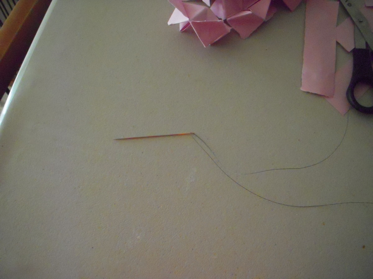 Thread doll making needle with about 42 to 60 inches of fishing line, depending on desired length of lei. 