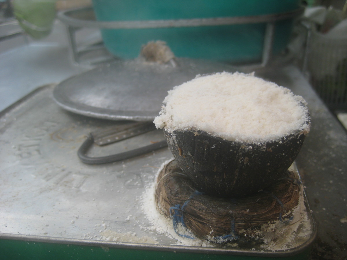 The coconut mold and the empty cooking oil can, instead of kettle, are used in steaming the rice cakes.