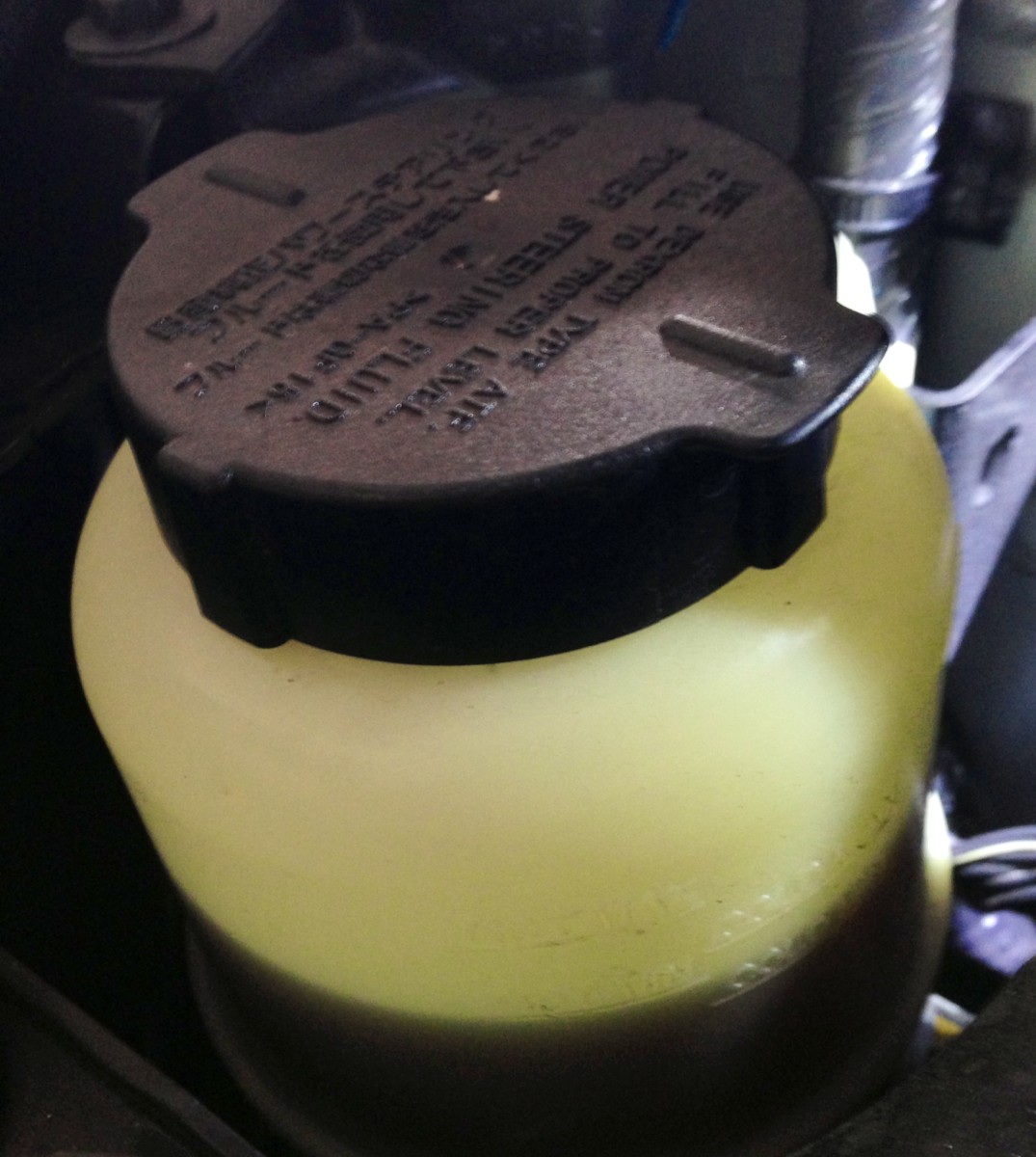This power steering fluid reservoir has marks for both "LOW" and "MAX" at both "cold" and "hot" engine temperatures.  Fluid can expand with heat, read the indicating marks on your car carefully.