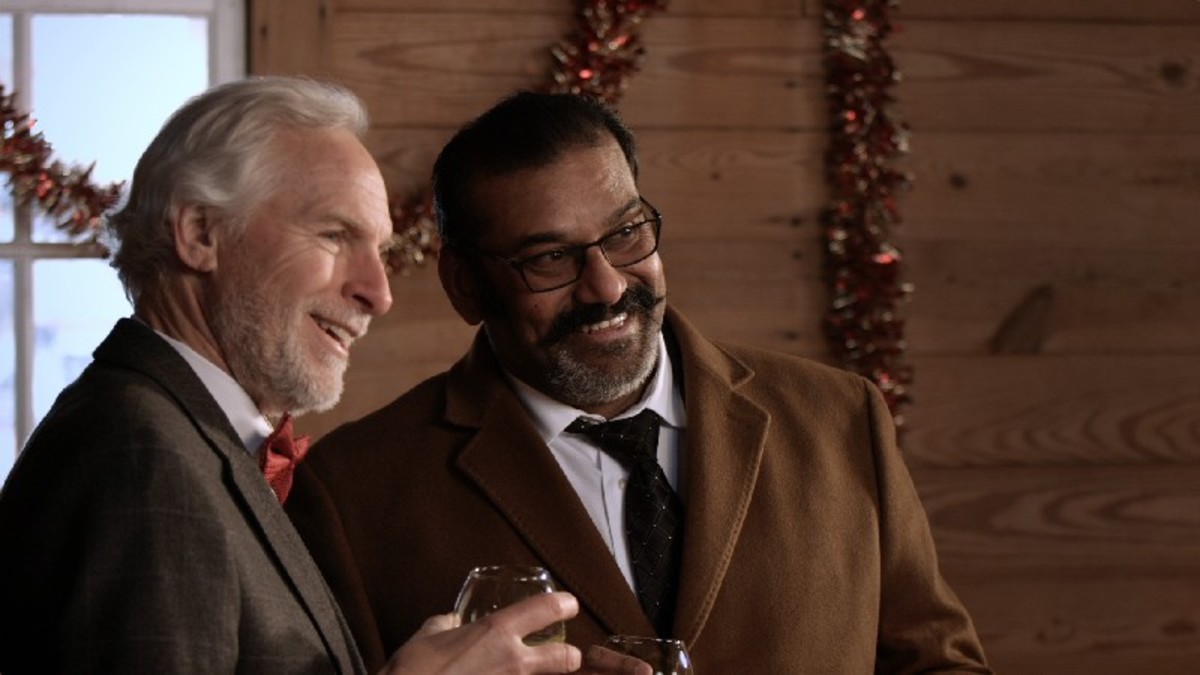 Nicholas Hodge (Tim Kaiser-L) and Agent Kumar (Napolean) share a laugh and a drink at a fundraiser to help the local soup kitchen
