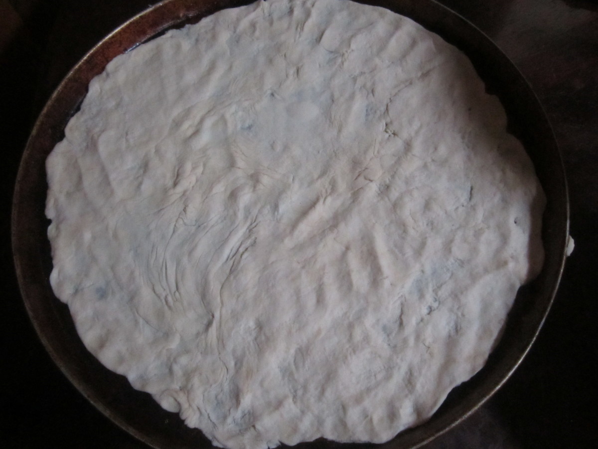 Spread out pizza dough by hand.