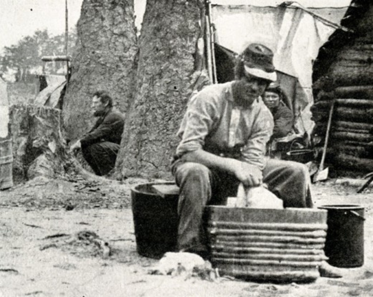 A soldier cleans his clothes in a metal tub