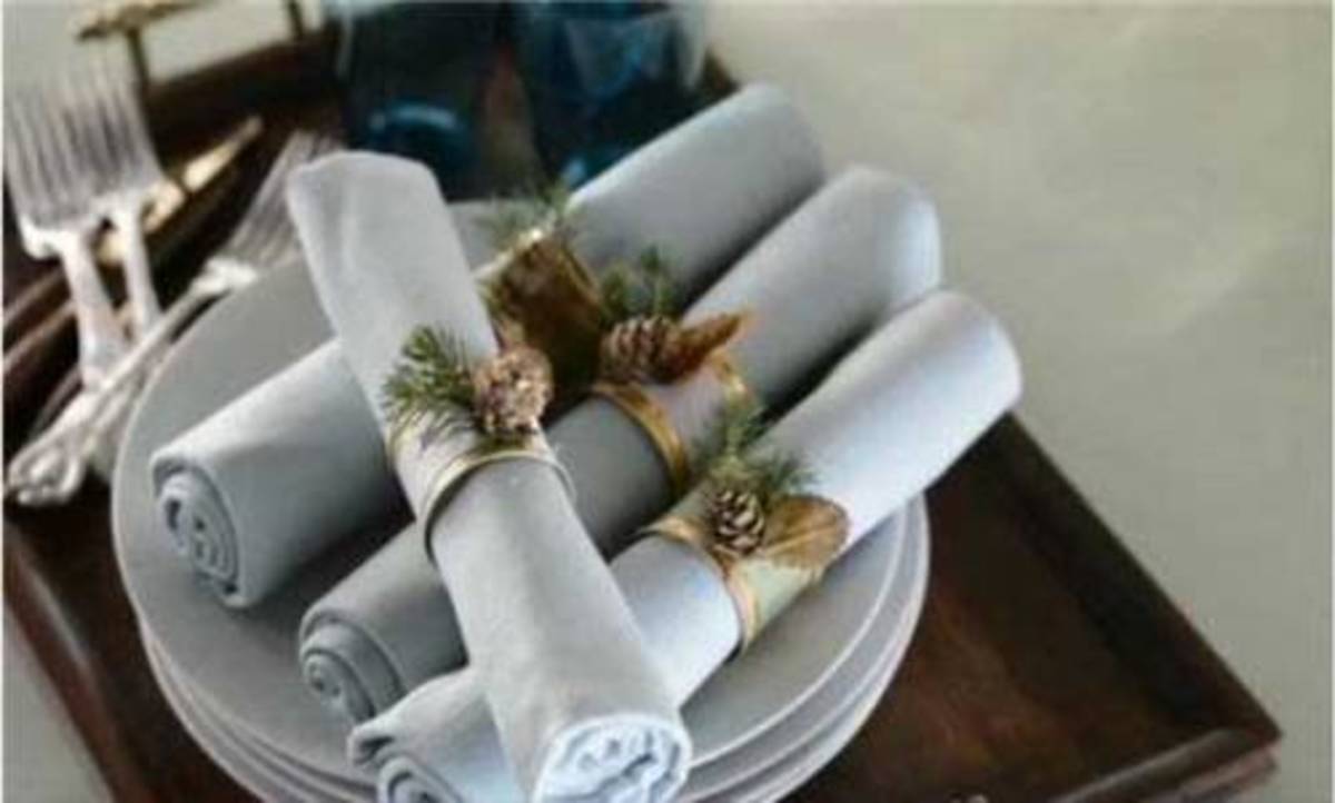 Holiday woodland-inspired napkin rings are rustic pinecones and sprigs of evergreen.