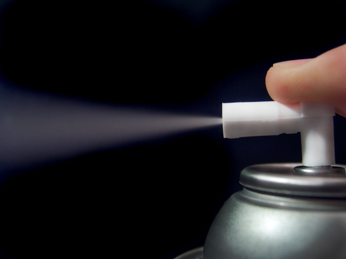 The index finger pressing on the spray can nozzle