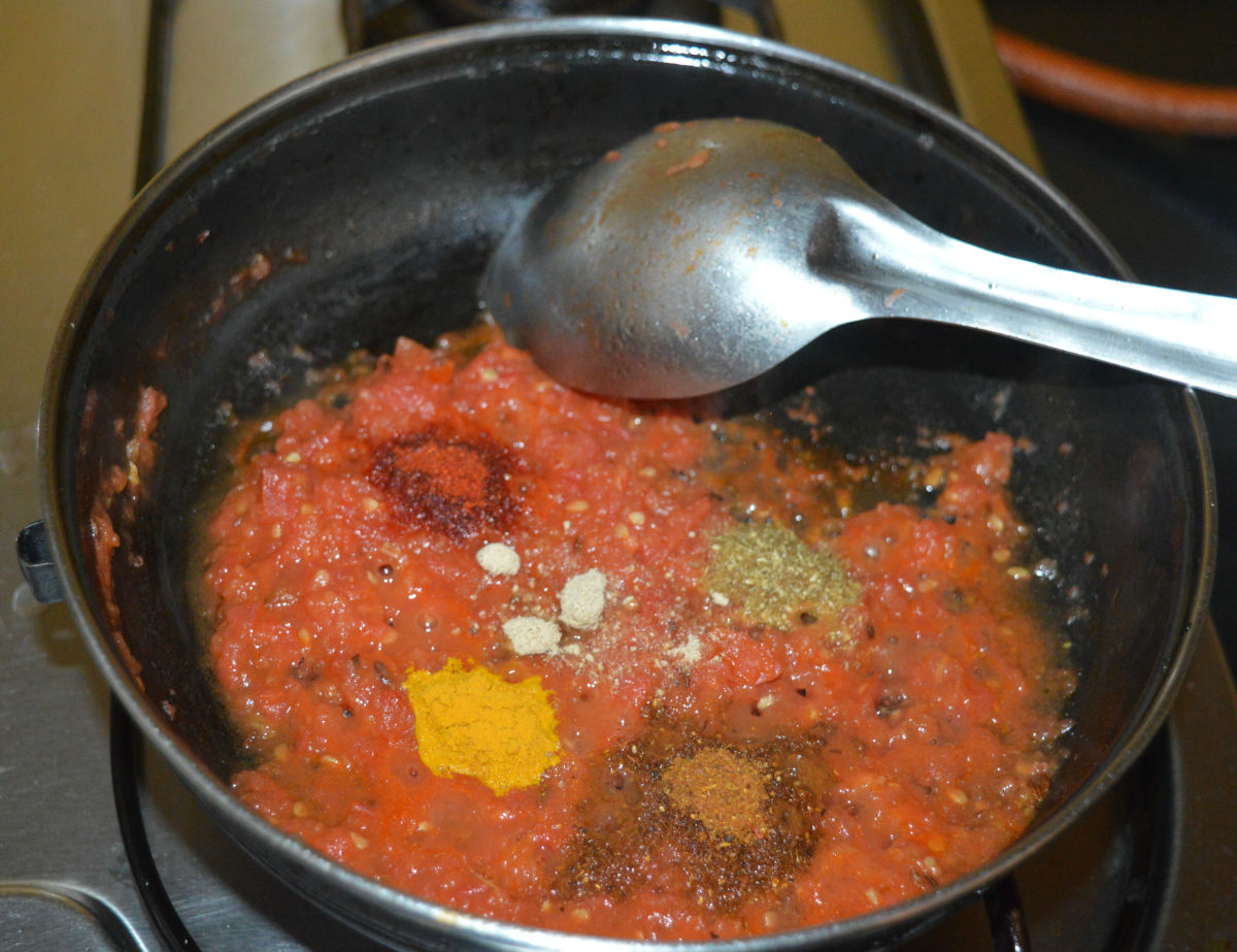 Step three: When the tomatoes become mushy, lower the heat to a minimum. Add turmeric powder, red chili powder, garam masala powder, amchur powder, coriander powder, sugar, and remaining salt. Saute the mixture for a minute.