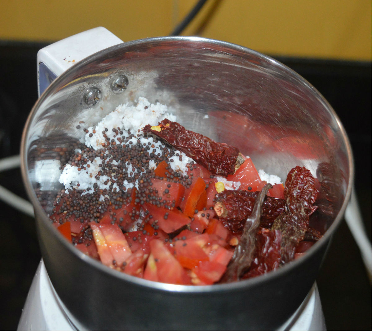 Step two: Add chopped tomatoes, broken dry red chilies, coconut gratings, and mustard seeds to a mixer jar. Grind to get a smooth paste. Add only a very small amount if needed. Set aside.