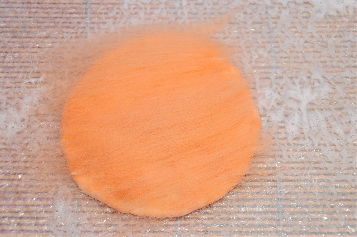 Cover the 2nd side of the template with a thin layer of orange merino wool roving.