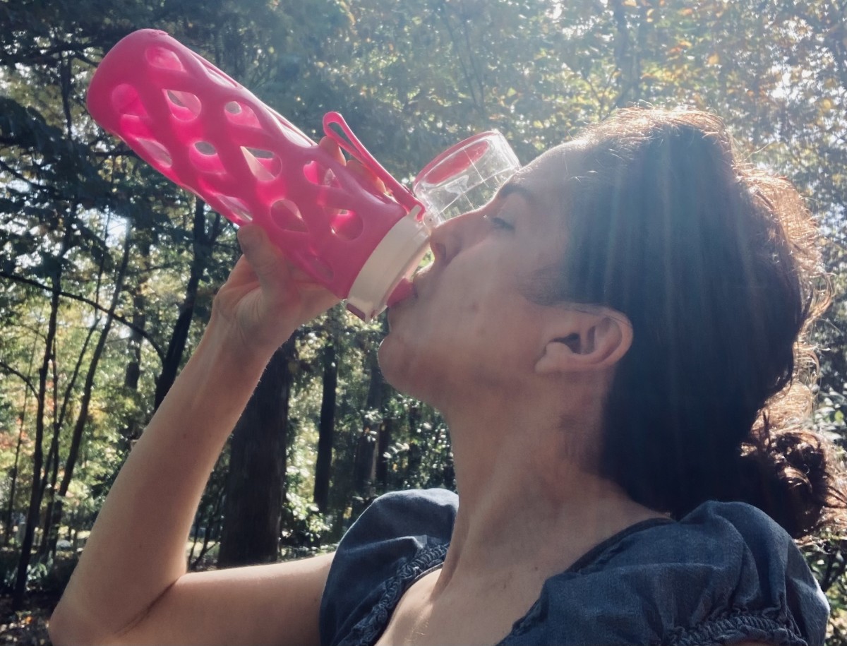 Woman drinking water to alleviate a hot flash 