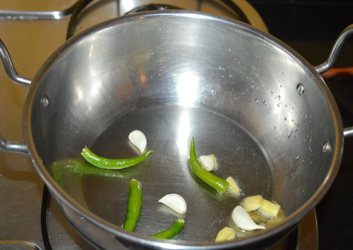 To the same pan, add garlic, broken green chilies, and ginger. Saute for a few seconds.