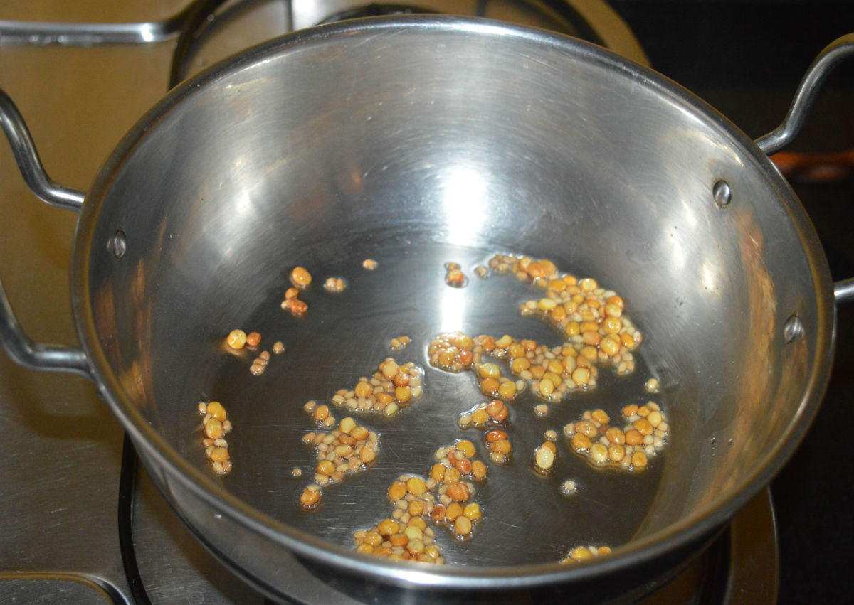 Step two: Heat a deep-bottomed pan. Add split Bengal gram and white lentils. Saute in oil until the lentils become golden brown. Add them to a mixer jar.
