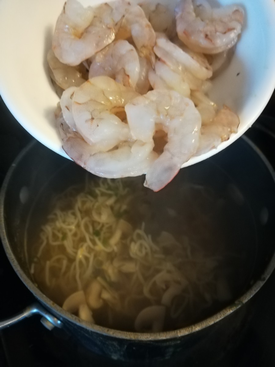 Putting the raw shrimp in the broth.