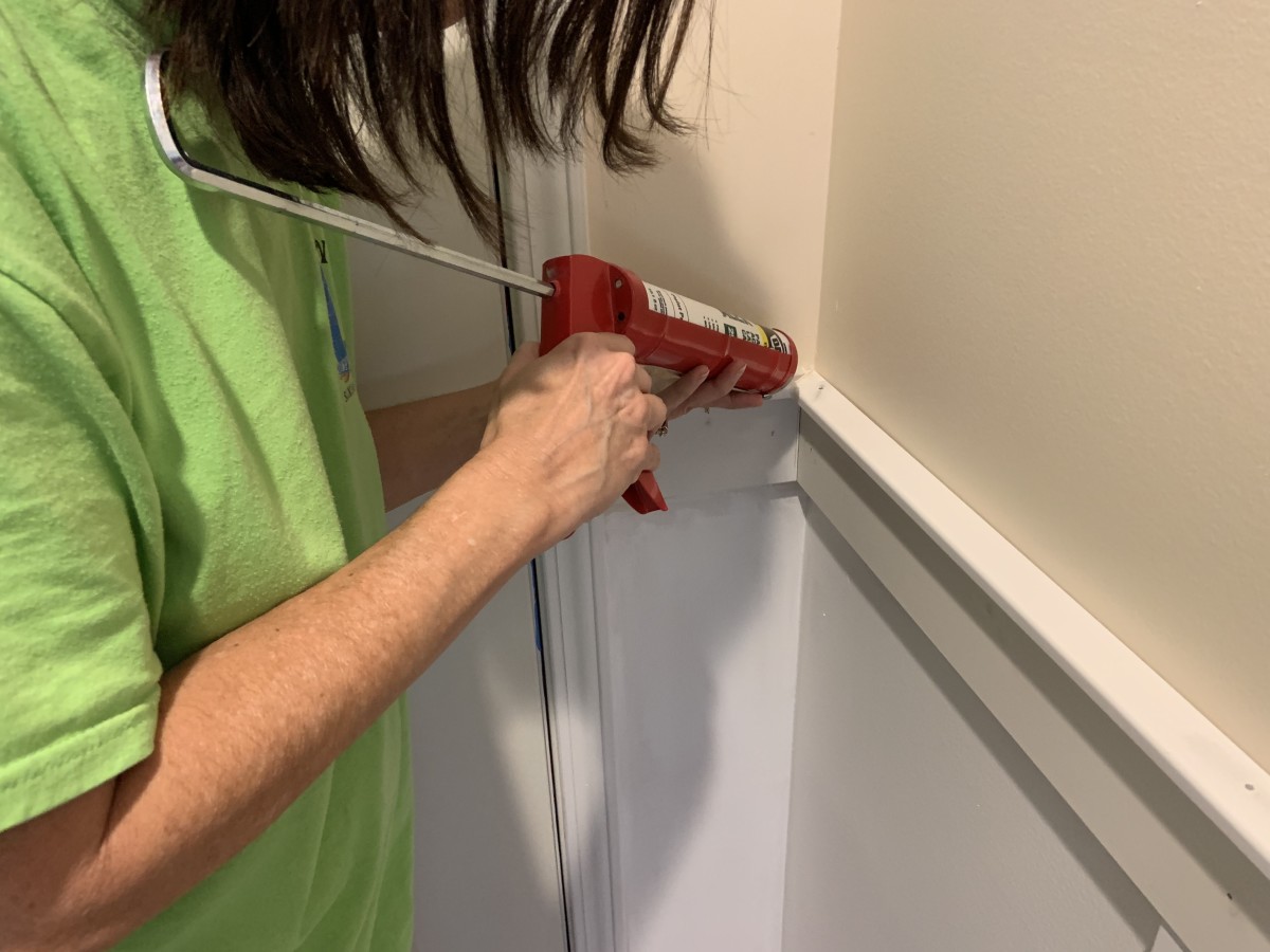 Applying caulk to the cracks in the corner to get it ready to paint. We had to put a small amount of caulk over the countersunk nails.