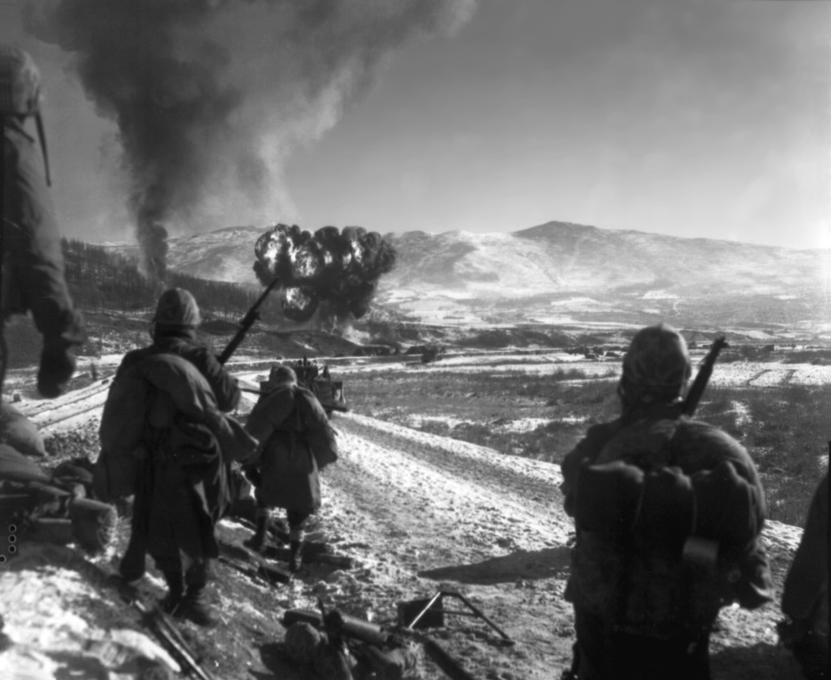 Marines watch F4U Corsairs drop napalm on Chinese positions in Korea during the withdrawal from the Chosin Reservoir. (1950)