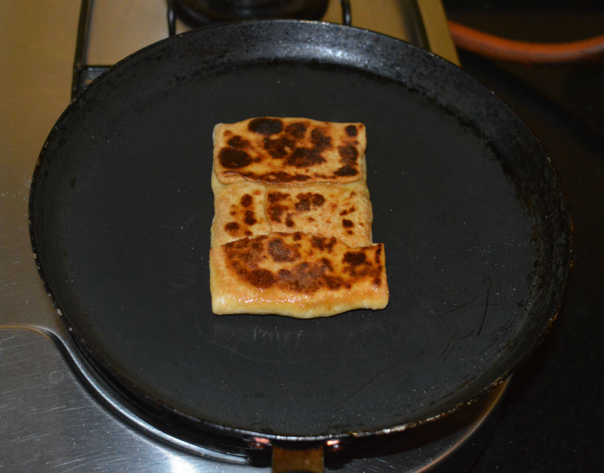 Continue flipping and roasting until done. Transfer the cooked paratha to a serving plate.