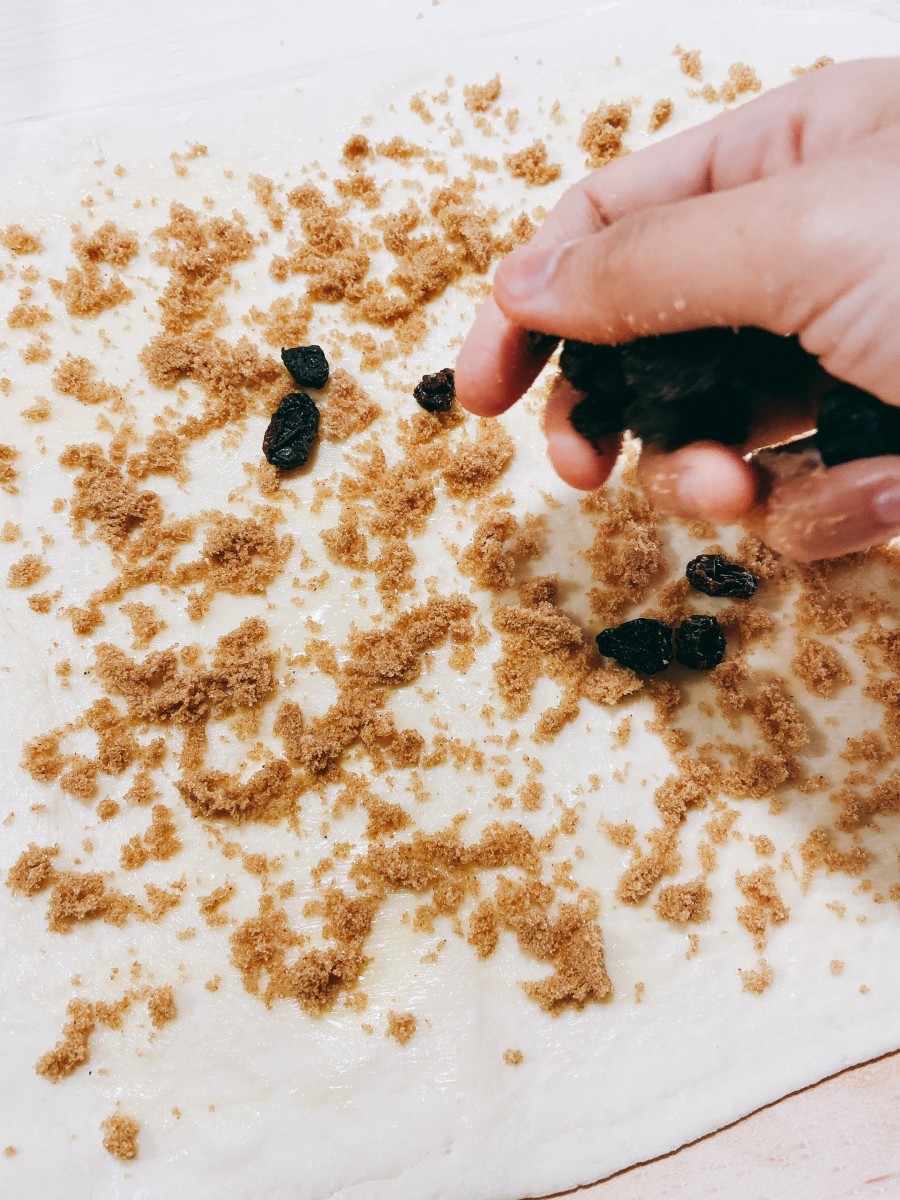 Sprinkle the dough with cinnamon sugar and then sprinkle the raisins on top.